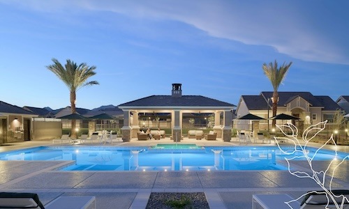 resort style pool with seating palm trees and a building behind it