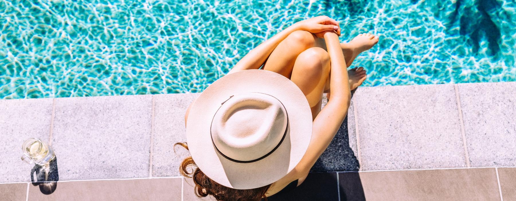 woman sitting beside a pool with a drink